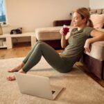 sportswoman-using-laptop-having-healthy-drink-while-relaxing-after-home-workout_637285-11645
